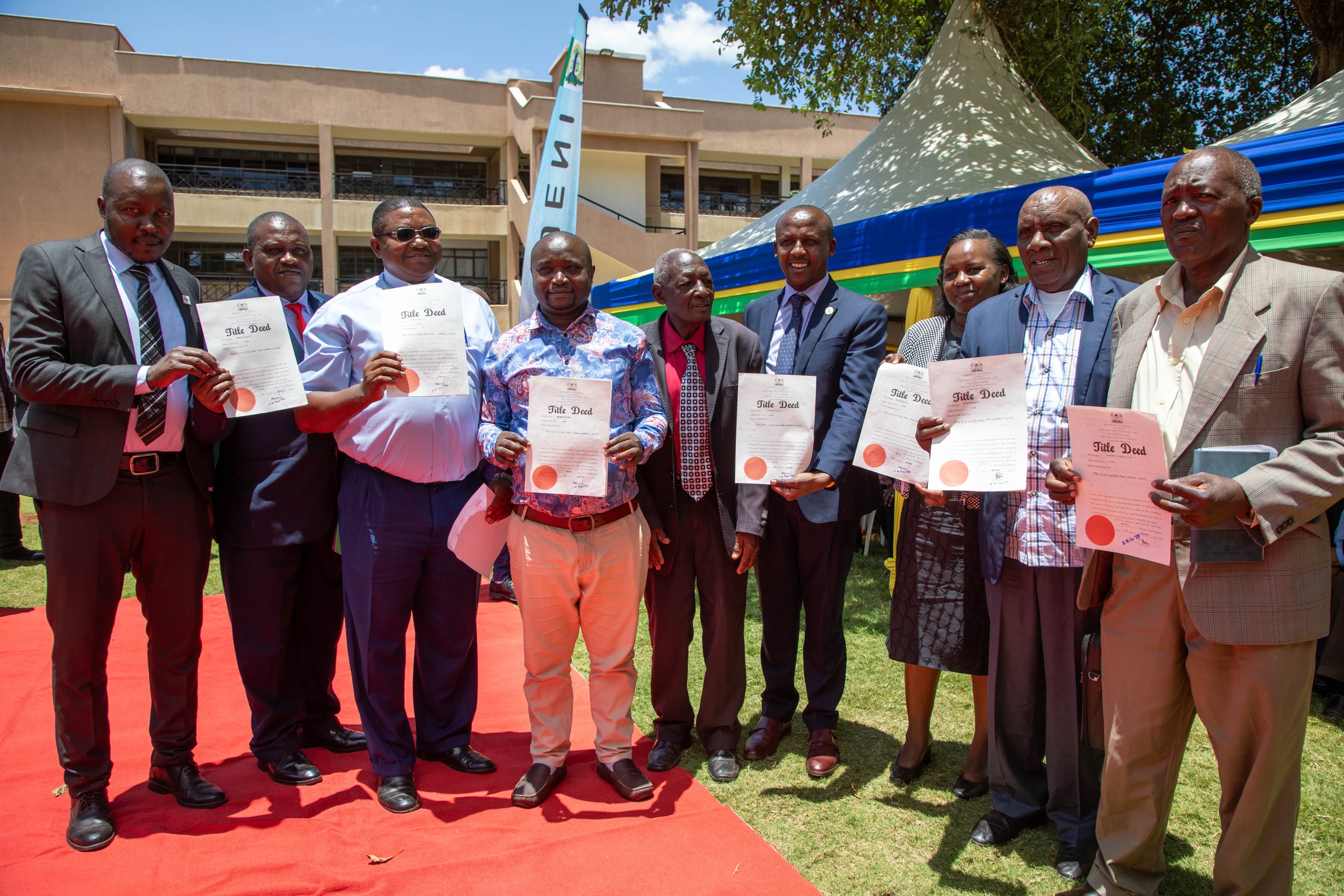 Makueni Governor, Mutula Kilonzo Jnr (C), display title deeds issued to public utilities outside his Wote Office.